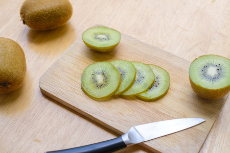 Fresh sliced kiwi fruit and knife on cutting boardの写真素材