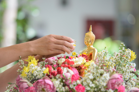 Pouring water over Buddha statue to signify cleansing for the New Year, Songkran festival tradition of thailandの写真素材