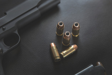 .45 Caliber hollow point bullets near handgun and magazine on leather furniture