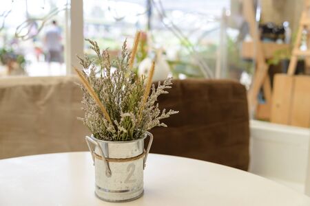 grass flowers in a vintage zinc vase on tableの写真素材