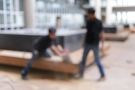 Abstract blurred image of  Two men carpenters use circular saw to cut the woodの写真素材