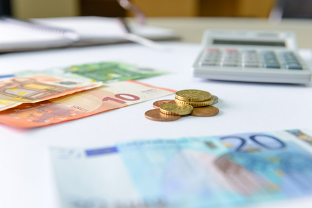 Euro money banknotes and coins counting with calculator, notebook on deskの写真素材
