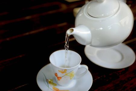 Time of Tea Break. Tea is pouring from teapot into a cup.の写真素材