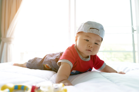 Portrait of asian baby  boy little 7 months old. wear a cap on the bed in his room