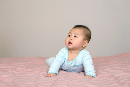Portrait of asian baby  boy little 7 months old. wear a cap on the bed in his room