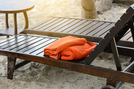 Empty wooden sunbed with orange towels on the beach. vacation concept