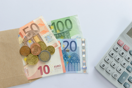 Euro money banknotes and coins counting with calculator on white backgroundの写真素材