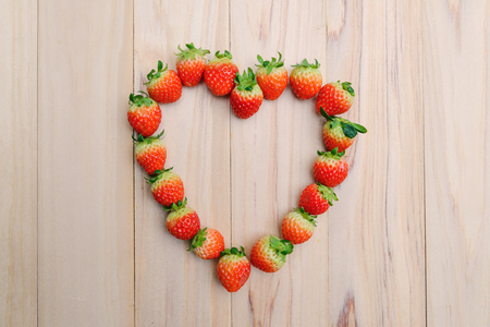 strawberries array heart shape on wooden table - Love conceptの写真素材