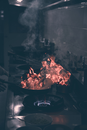 Chef cooking and doing flambe on food in restaurant kitchenの写真素材