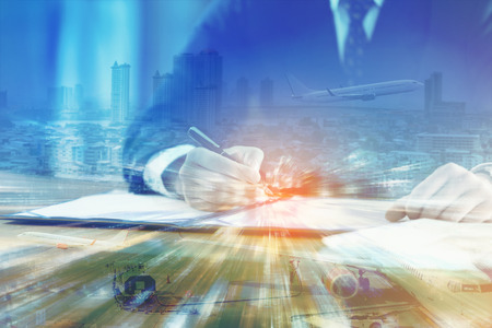 Double exposure of business man signing contract document in office with cityscape and ground crew serviced airplane - Global logistics network business connection conceptの写真素材