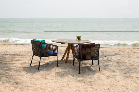 empty wooden table with two chairs at beach restaurantの写真素材