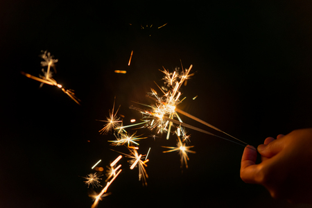 Female hands holding sparkler with night background - bright festive Christmas or New Yearâs Eveの写真素材