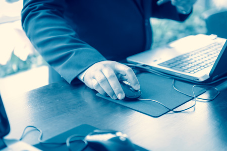 hand of businessman touching a computer mouse with laptop computerの写真素材