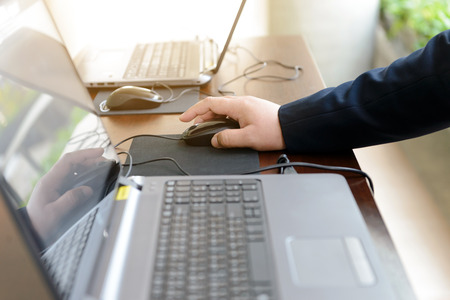 hand of businessman touching a computer mouse with laptop computerの写真素材