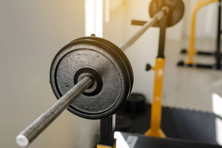 Side view of barbell on the rack in fitness gym. Weight Training Equipment. Health care concept.