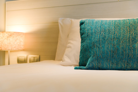 stacking of pillows on bed, white bed sheets with light lamp decoration interior of bedroom.の写真素材