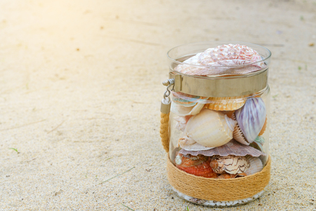 Variety of sea shells in glass jar on the sand beach with copy space. holiday conceptの写真素材