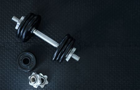 Top view of Iron dumbbells or weights on black floor with copy space for text. Flat lay composition. Health care concept.の写真素材