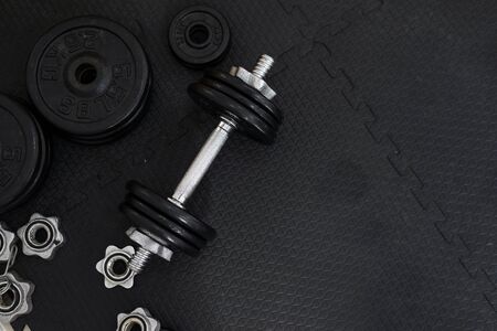 Top view of Iron dumbbells or weights on black floor with copy space for text. Flat lay composition. Health care concept.の写真素材