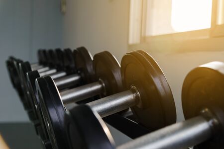 Rows of black dumbbell set on rack in the gym. Weight Training Equipment. Health care concept.の写真素材