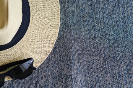 straw hat with black ribbon and sunglasses on sofa with free space, vacation travel in summer conceptの写真素材
