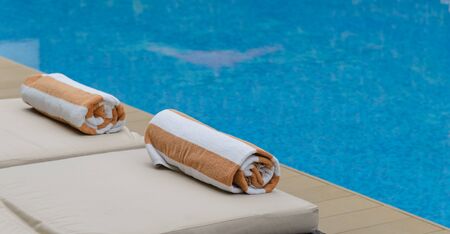 Roll soft towel on a sun bed near a swimming pool.