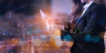 Double exposure of businesswoman using digital tablet with city scape and network connection diagram