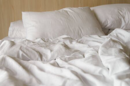 wrinkled white blanket with soft pillows on comfortable bed in the morning. messed up after nights...