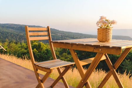 flowerpot on wooden table and chairs on terrace. Beautiful seating with landscape mountains view...
