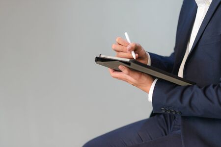Body shot of business man in suit sitting and working with digital tablet