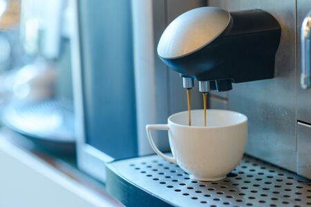 White cup standing on grating of automatic coffee maker machine. Coffee pouring in the cup. Coffee break conceptの写真素材