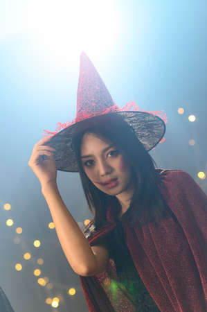 Portrait of beautiful young woman in witch halloween costume wear witches hat over spooky dark magic...