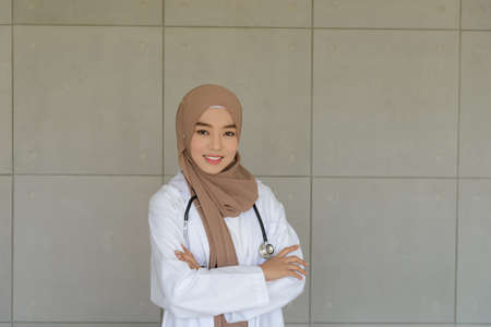 Portrait of Young muslim female doctor wearing doctor uniform and Hijab with stethoscope posing and...