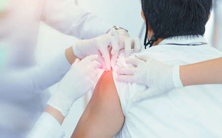 Close-up doctor or nurses female hand with syringe doing injection vaccine, flu, influenza in the shoulder of senior man. healthcare conceptの写真素材