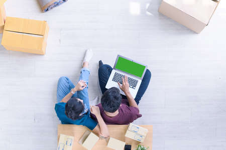 Top view of young asian couple working online marketing on laptop computer with cardboard parcel...