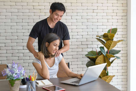 Young asian couple wear casual clothing relaxing while sitting at big wooden table in modern kitchen...