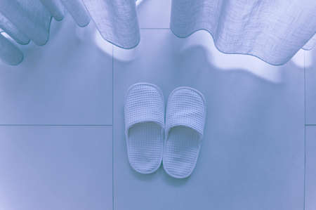 White slippers by white sheer curtainsの写真素材