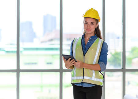 Portrait of female construction engineer workers in yellow hardhat with a tablet computer in...