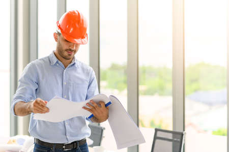 Portrait of construction engineer manager workers in orange hardhat and looking layout plan. posing...