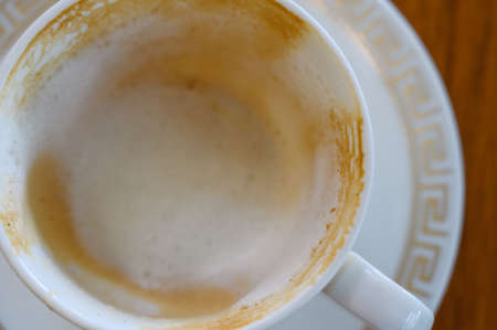 Top view ofÂ white foam in empty hot coffee cup after drink on wood table in cafe