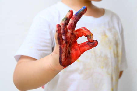 Colourful painted child showing hand fingers sign ok isolated on white background. Close up copy spaceの写真素材