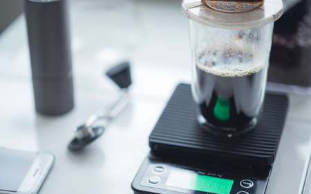 make drip brewing coffee. Glass on weighing machine with dripper and paper filter on pouring process. Home coffee lifestyle conceptの写真素材