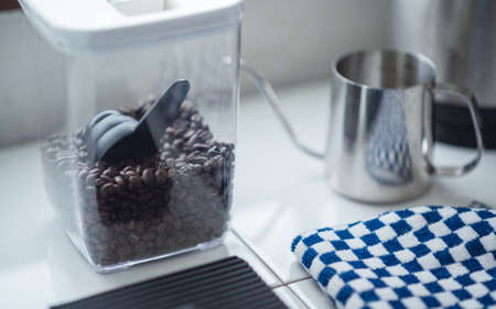 coffee beans and spoon in plastic transparent box with lid on table. Home coffee maker lifestyle conceptの写真素材
