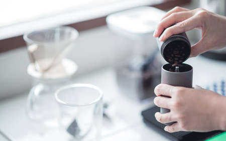 Barista women grinding coffee beans with manual grinder to making brew coffee at home. coffee drip equipment. lifestyle conceptの写真素材