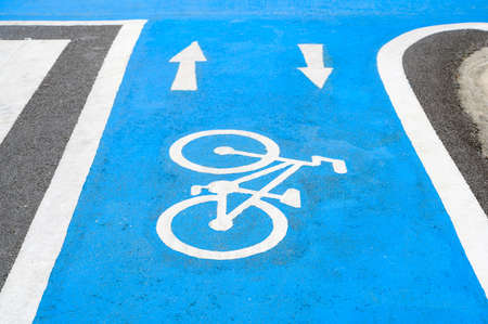 Blue bicycle lane on road with white bicycle icon and arrow. Empty Bicycle way for bikeの写真素材