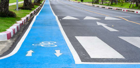 Blue bicycle lane on road with white bicycle icon and arrow. Empty Bicycle way for bike