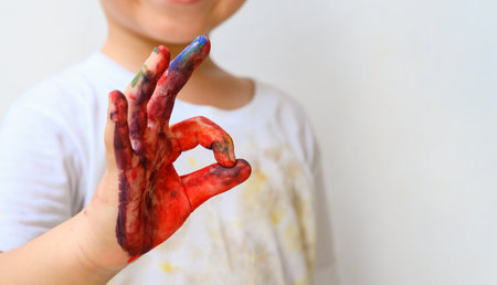 Colourful painted child showing hand fingers sign ok isolated on white background. Close up copy spaceの写真素材