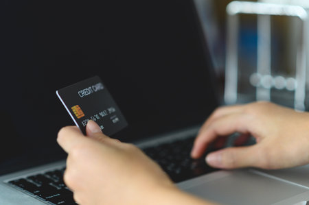 Close up woman hands holding credit card and using laptop shopping purchasing online. e-commerce, internet banking, checking balance, banking service, paying by credit card, making paymentの写真素材