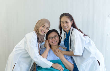 Group photo of muslim doctor, female doctor and elderly patient in hospital room. smiling and looking at camera. takes care and cheerful conceptの写真素材