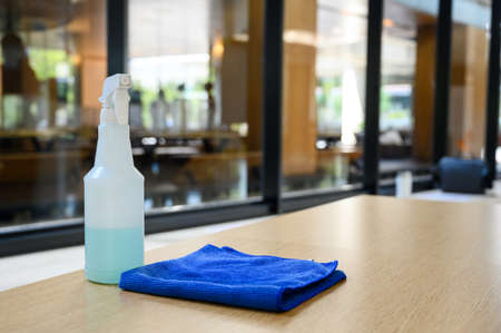 cleaner disinfectant spray bottle with blue microfiber cloth on table. Cleaning products for...